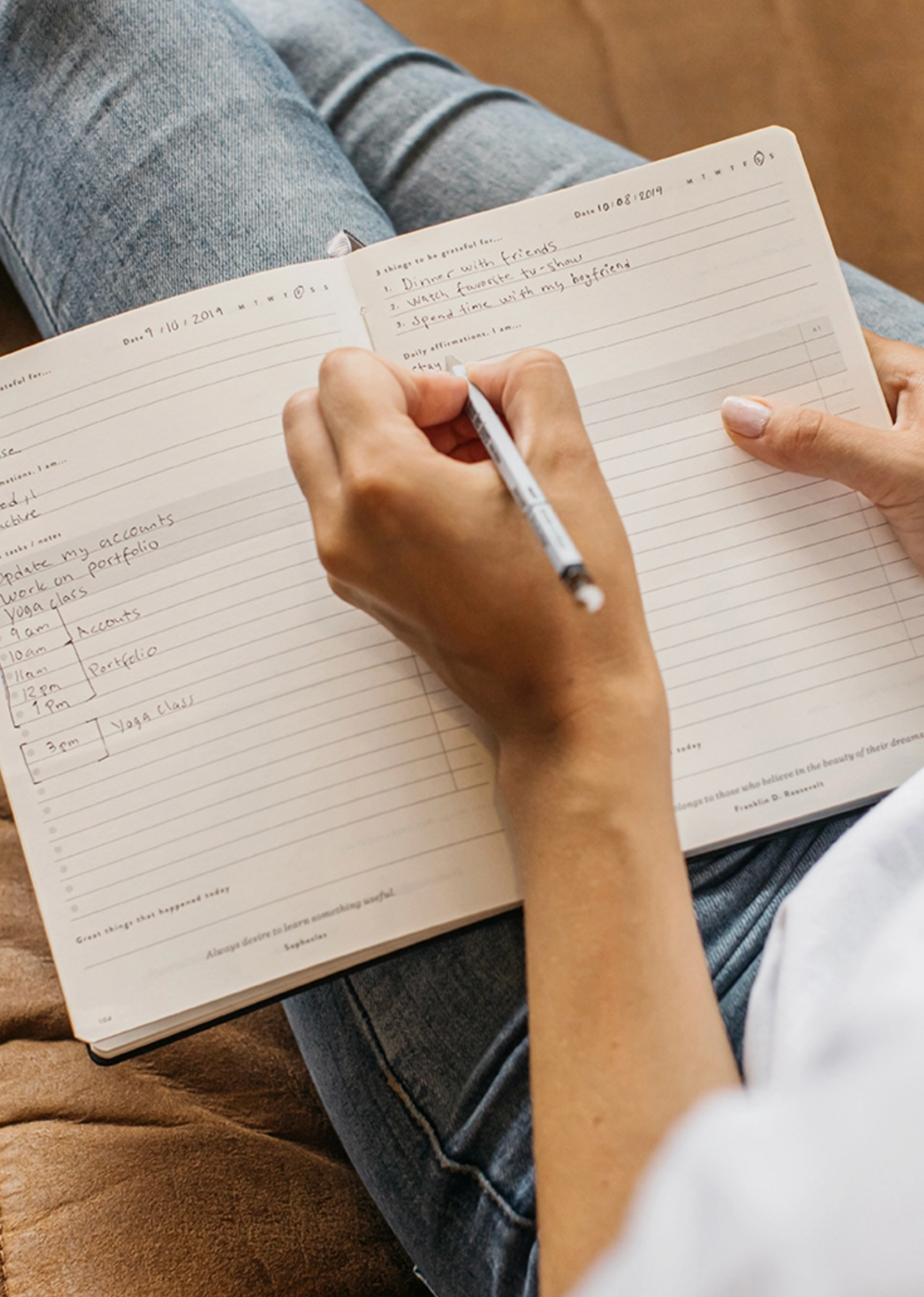 Photo of the modern women writing in the page layout of blackbird designs holistic daily planner, ideal for setting and achieving meaningful goals.